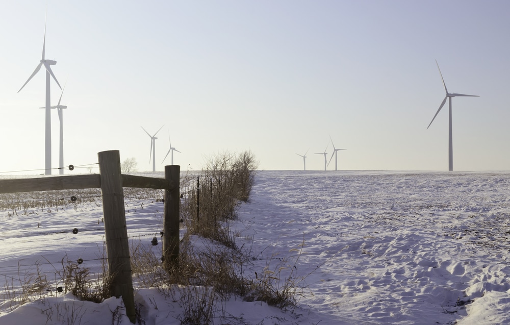 Agricultural landscape altered by technology for commercial production of electric power in northern Illinois Recently build wind turbines tower above snowy farmland in winter