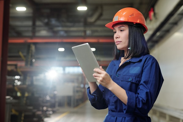 predictive maintenance and preventive maintenance differencetechnician in orange hard hat looks at tablet